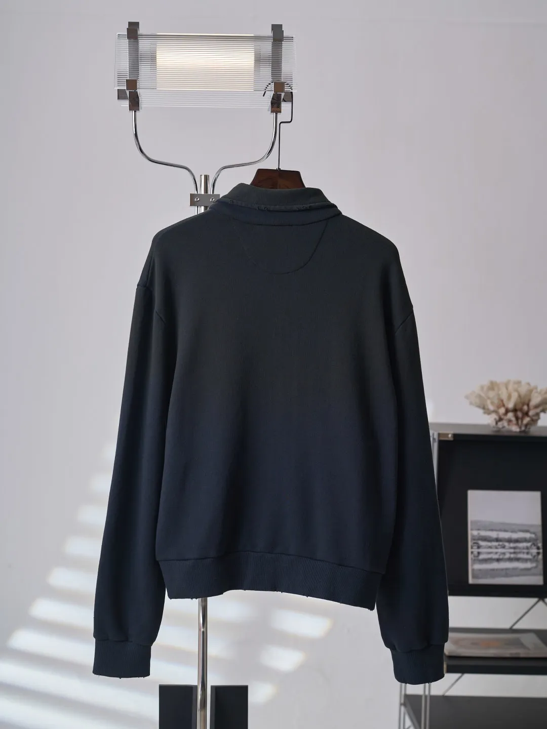 [Real auction] Acne Studios Retro distressed letter print zipper jacket [In Stock] Logo stamp at front, side-seam pockets, and ribbed cuffs and hem. Regular fit, just above the waist. It adopts a 3-strand composite fleece structure with 32 counts for the top layer and 40 counts for the bottom layer, with a weight of g/㎡. The 32-count yarn on the top layer is fine and smooth, giving the surface a smooth touch and excellent anti-pilling properties; the 40-count 3-ply yarn on the bottom layer is treated with a raising process to form a rich and soft fluff layer, providing excellent warmth and skin-friendly wrapping. With 21 2×2 ribs, the g/㎡ weight ensures that the collar, cuffs and hem have excellent tensile fatigue resistance and shape retention capabilities. During piece dyeing, the entire fabric is immersed in the dye vat after weaving, and the dye molecules fully penetrate into the fibers, ensuring full, deep colors and excellent color fastness. Each batch of dyeing produces subtle differences, making the color tone of the single product unique. On this basis, the paint is sprayed irregularly on the surface of the garment through manual spray painting to create a splash-like retro effect. The distressed processing of holes causes the color to fade and mottle in parts. The ribbed trim is also treated to form slight whitening and fluffing, which visually echoes the spray-painted effect on the body, making the new clothes appear as if they have been worn for a long time and exposed to the sun. The front logo stamp uses a slurry printing process. The printing slurry contains a special microcapsule foaming agent. After being baked at high temperature, the slurry layer expands to form three-dimensional bulges, and the surface presents a granular texture similar to inkjet paint. This process simulates the effect of random drops of pigment after being atomized during spray gun spraying. The edges of the pattern present a natural feathering transition, rather than the rigid boundaries of glue printing. The printing surface has a fine graininess and soft elasticity to the touch, forming a closed loop of the process with the distressed effect of the spray painting on the body.